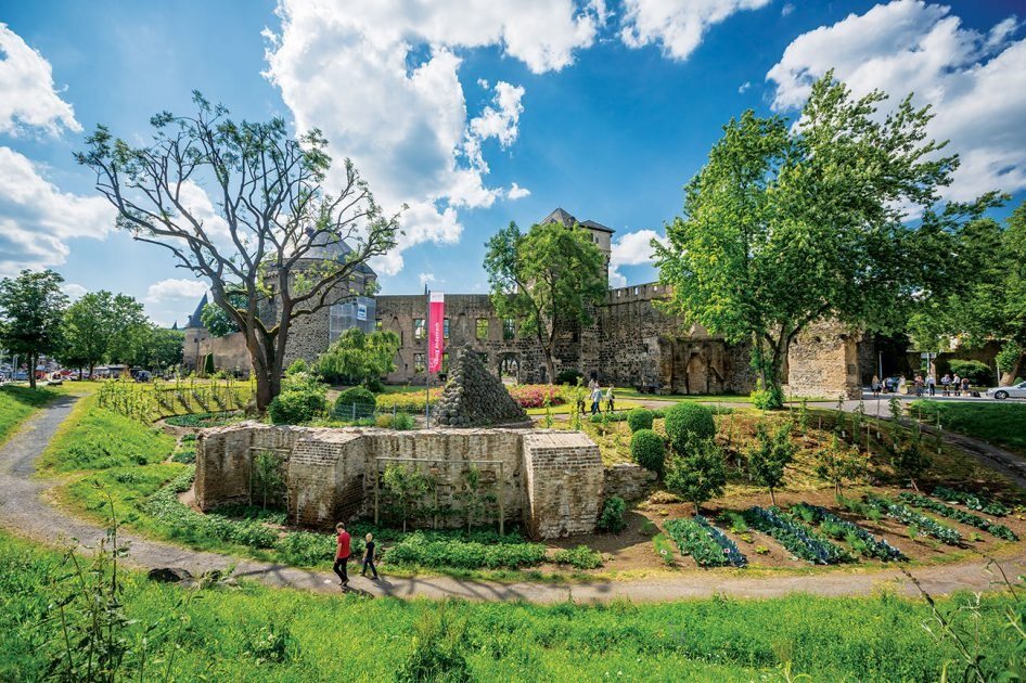 Cidade comestível de Andernach, pessoas andando entre as plantações que estão integradas aos jardins da cidade.