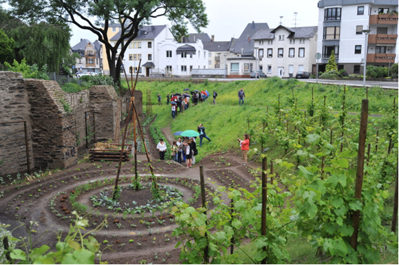 Cidade comestível de Andernach, pessoas andando entre as plantações que estão integradas aos jardins da cidade. 