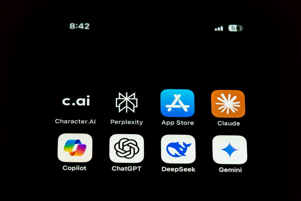 Tela de um smartphone mostrando ícones de aplicativos de inteligência artificial, incluindo Character.AI, Copilot, Claude, Perplexity, Gemini, ChatGPT e DeepSeek
